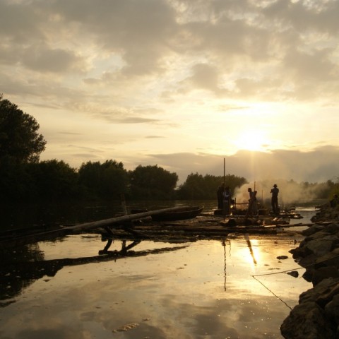 Powiększ obraz: Tratwa flisacka na Sanie w pobliżu brzegu podczas zachodu słońca